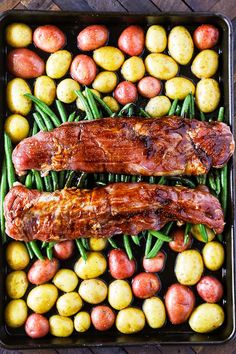 two large pieces of meat sitting on top of green beans and potatoes