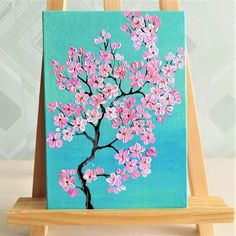 an easel with a painting on it that has pink flowers painted on the side