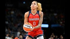 a female basketball player holding a ball in her right hand and looking up at the sky