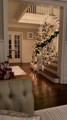 a decorated christmas tree sitting on top of a wooden floor next to a stair case