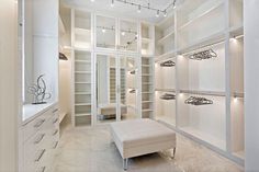 a walk in closet filled with lots of white shelves