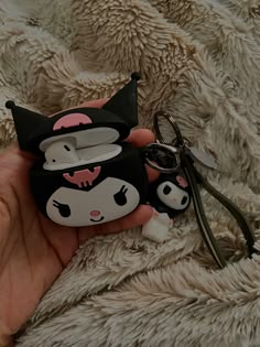 a hand holding a small black and white cat shaped keychain with scissors in it