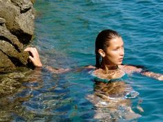 a woman is swimming in the water near some rocks