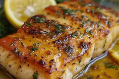 two pieces of fish on a plate with lemons and parsley