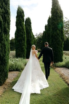 a bride and groom walking through the gardens