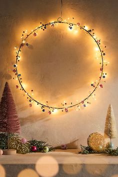 a christmas wreath hanging on the wall with lights around it and decorations in front of it