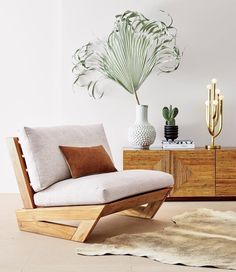 a living room with white walls and wooden furniture, including a plant in the corner