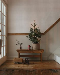 a small christmas tree sitting on top of a wooden table next to a train set