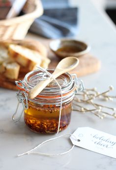 a jar filled with honey sitting on top of a table next to bread and spoons