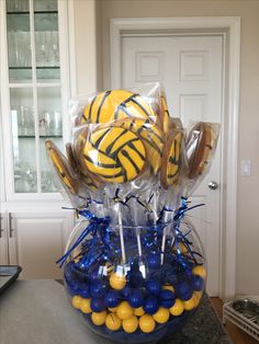 a clear vase filled with yellow and blue candies, lollipops and balls