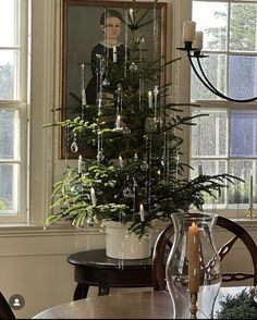 a christmas tree with candles and ornaments in front of a portrait hanging on the wall