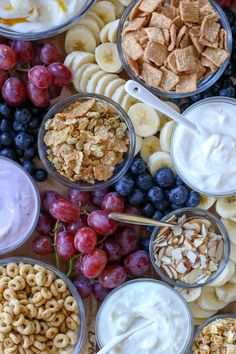 an assortment of snacks and yogurt are arranged on a wooden table with grapes