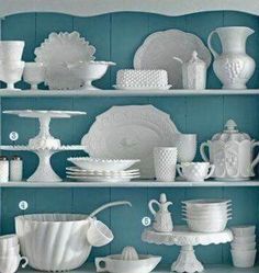 the shelves are filled with white dishes and cups