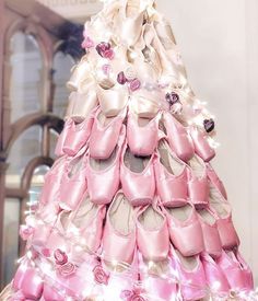 a dress made out of pink and white shoes with roses on the bottom, sitting in front of a doorway