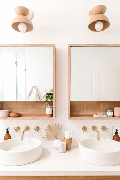 two sinks in a bathroom with mirrors and lights on the wall above them, next to each other