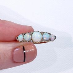 "This Victorian ring was handcrafted in England around 1900. It's a glimmery little stunner featuring five round cabochon opals patterned with 10 rose cut diamonds. The largest opal can be found at the center of the ring face, it measures 5.3 mm in diameter and 3.3 mm in depth. This piece is a size 8.25 and it weighs 4.5 grams. The ring face measures 7.5 x 22.5 and it sits 5.4 mm off the finger. It bears the gold purity mark, \"18 C\". Opals look like the universe and all her colors inside one t Victorian Style Opal Round Rings, Antique Style Round Opal Ring, Antique Hallmarked Opal Ring, Opal Jewelry With Rose Cut Diamonds, Round Opal Jewelry With Rose Cut Diamonds, White Gold Opal Ring With 17 Jewels, Victorian Style Round Opal Ring, Victorian Round Opal Ring Hallmarked, Victorian Hallmarked Opal Ring