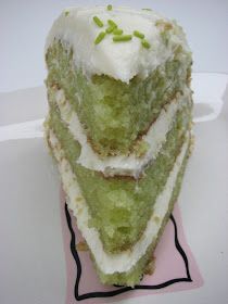 a piece of green cake with white frosting and sprinkles on top