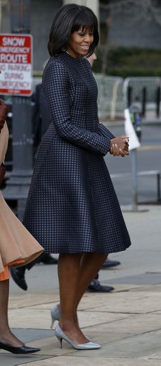 the first lady is walking down the street with her hand in her other hand and another woman wearing a blue dress