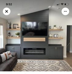 a living room with a couch, television and shelves on the wall in front of it