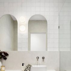 a white bathroom with two sinks and mirrors