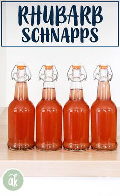 four glass bottles filled with ketchup sitting on top of a wooden table next to a sign