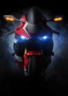 a red and white motorcycle with its lights on in the dark night time, it appears to be driving