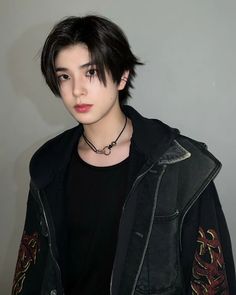 a young man with black hair wearing a leather jacket