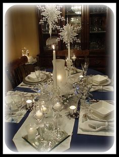 a dining room table is set with white dishes and silver place settings for dinner guests