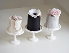 three tiered cakes with white and black frosting, decorated with flowers on top