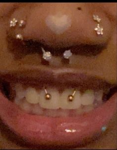 a close up of a person's mouth with gold and silver nose piercings