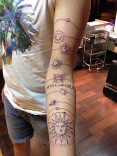 a person with a tattoo on their arm that shows the sun and planets in space