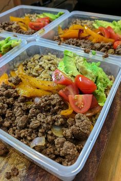 four plastic containers filled with food on top of a wooden table