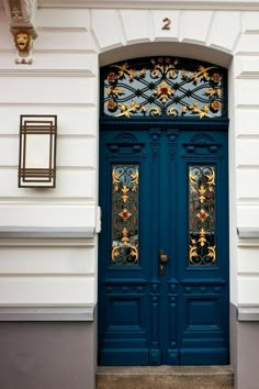 a blue door with ornate iron work on the top and bottom part, in front of a white building