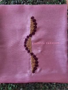 an embroidered purple cloth with gold thread and beads on the side, sitting on top of some green plants