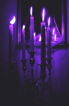 candles are lit in front of a mirror with purple lights on it and one candle is glowing