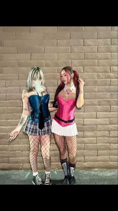 two women dressed up in costumes standing next to each other near a brick wall with their hands on their hips