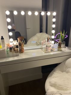 a vanity with lights on it and a chair in front of the mirror that is sitting next to it