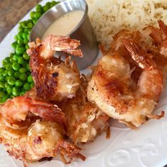 some shrimp and rice on a plate with peas