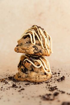 two chocolate chip cookies with white icing stacked on top of each other in dirt