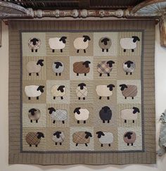 a quilt with sheep on it hanging from the ceiling in front of a wall decoration