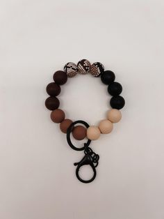 the black, brown and white beaded bracelet with scissors is shown on a white surface