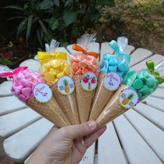 a person holding up some ice cream cones with bows on them in front of a bench