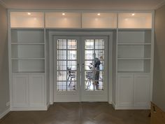 an empty room with two doors and some shelves on either side of the glass door