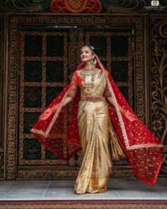 a woman in a gold sari and red shawl is standing on the stage