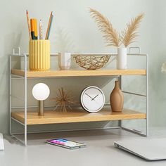 a laptop computer sitting on top of a desk next to a shelf filled with office supplies