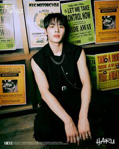 a young man sitting on the ground in front of posters and signs with his hands crossed