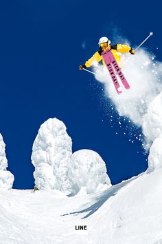 a person on skis jumping in the air with snow behind them and blue sky above