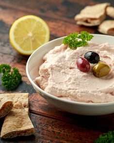 a bowl filled with hummus and olives next to crackers