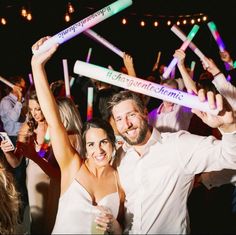 a man and woman are posing for a photo with their arms in the air at a party