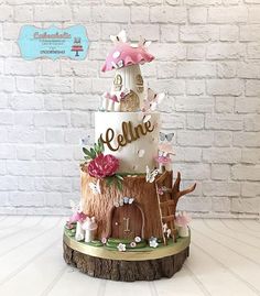 a three tiered cake decorated with mushrooms and flowers on a wooden stand in front of a brick wall